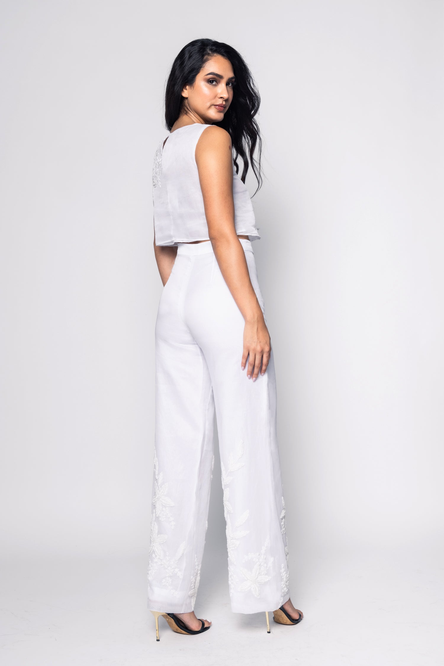 Woman wearing a white beaded outfit with a plain background