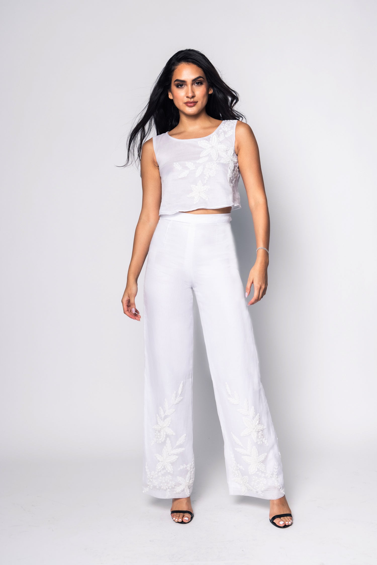 Woman wearing a white beaded outfit with a plain background