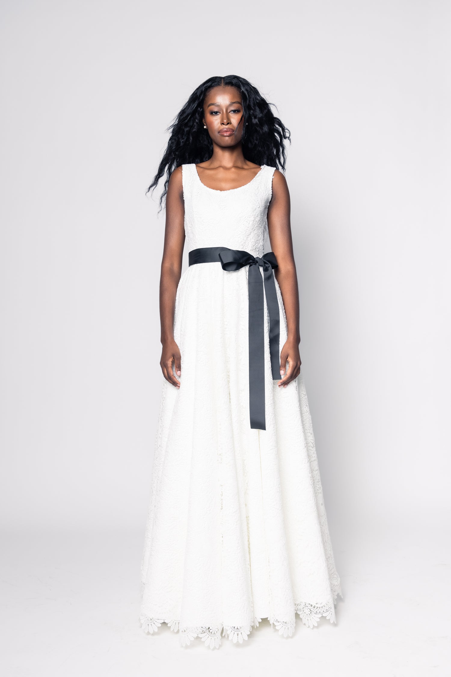 Woman wearing a white dress with a black belt on a white background