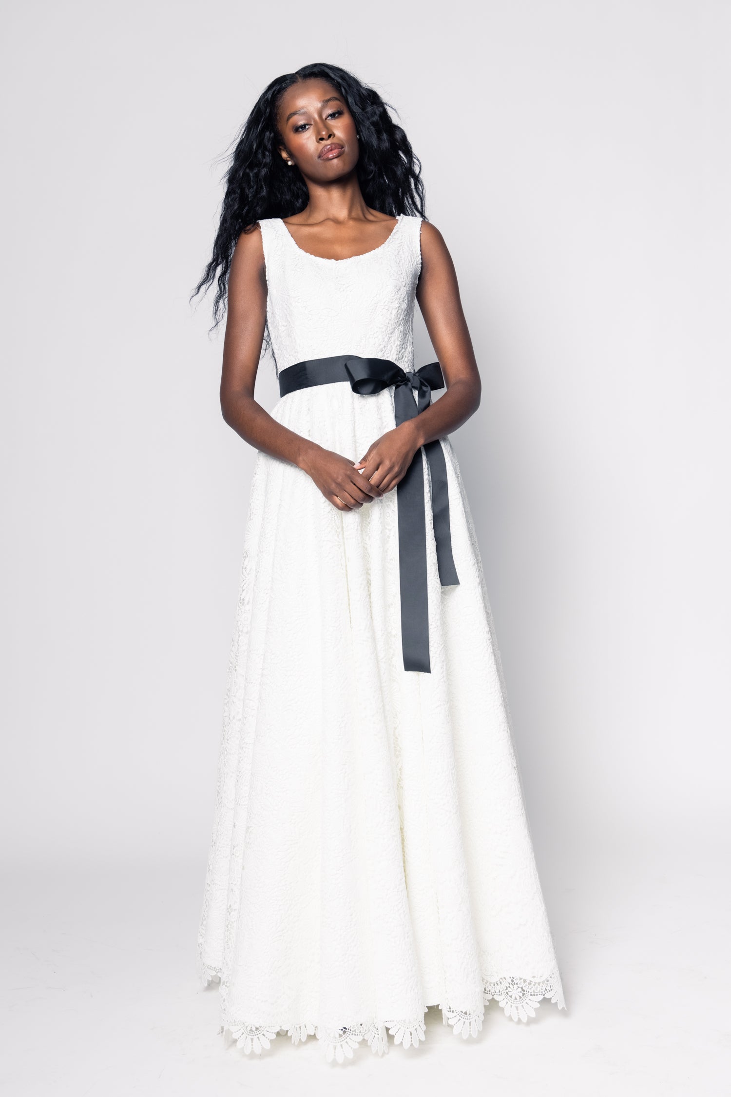 Woman wearing a white dress with a black belt on a white background