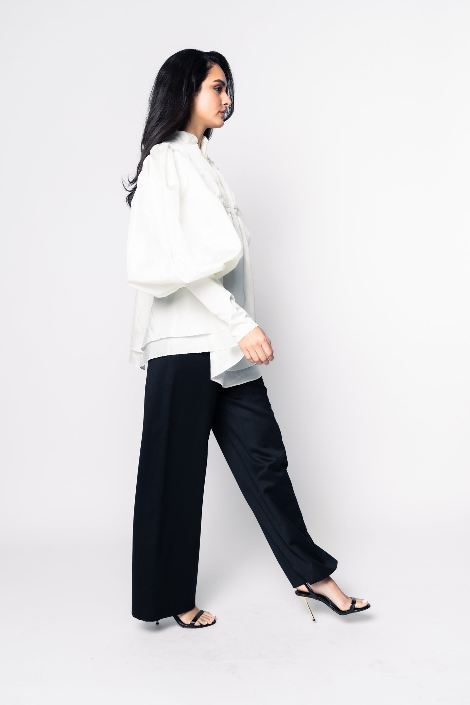 Woman wearing a white top and black pants on a white background