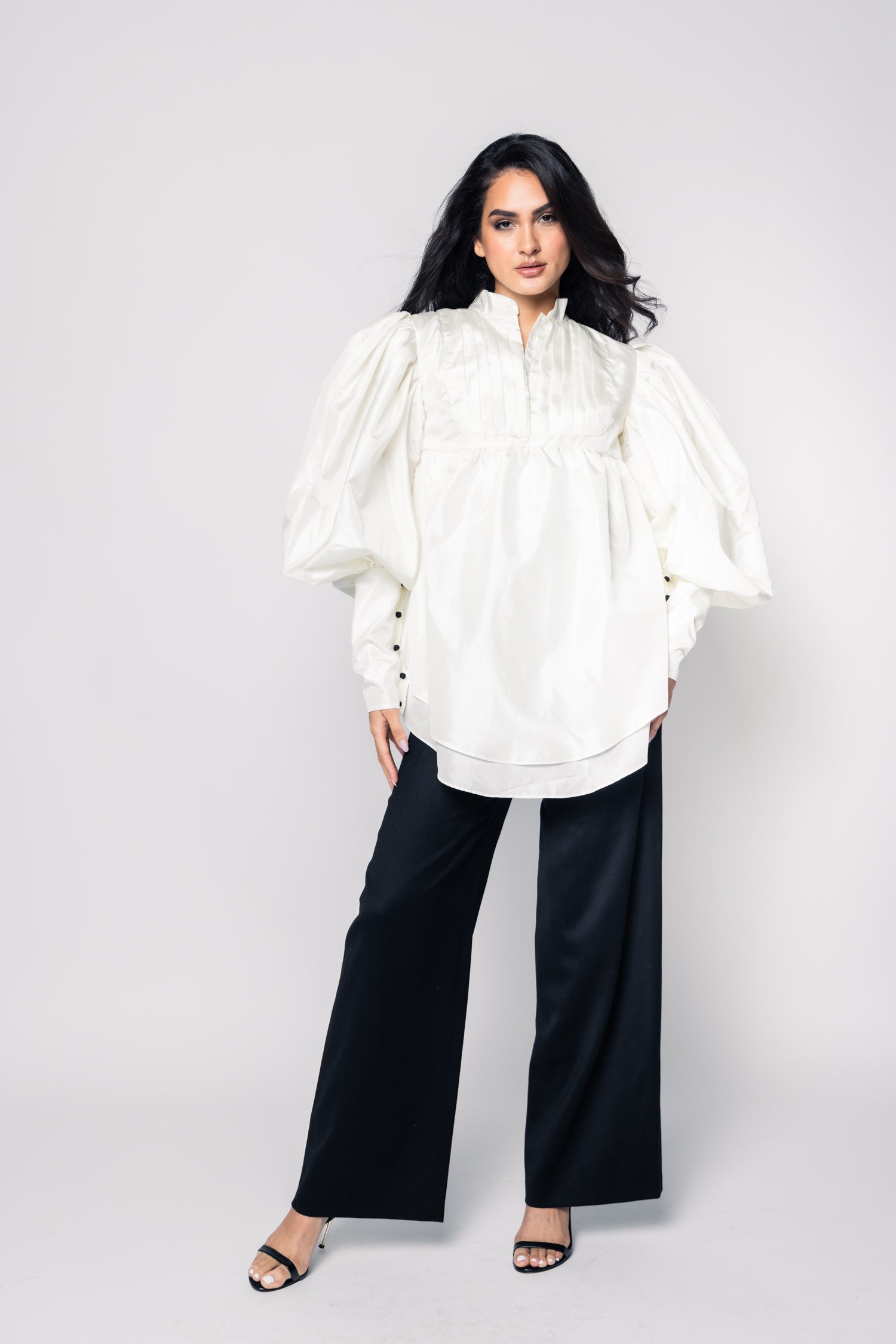 Woman wearing a white blouse and black pants on a white background
