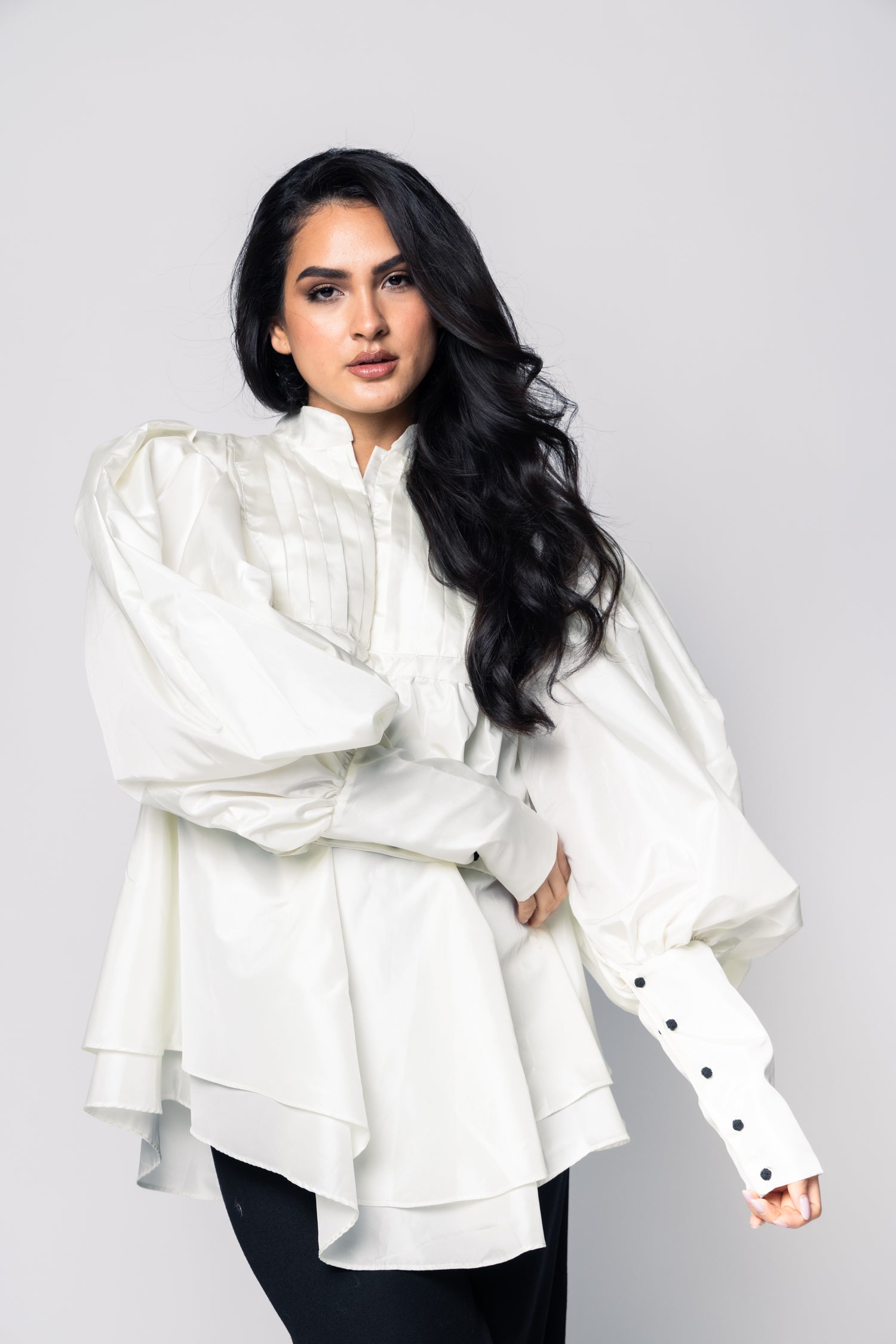 Woman wearing a white blouse with black buttons on a gray background