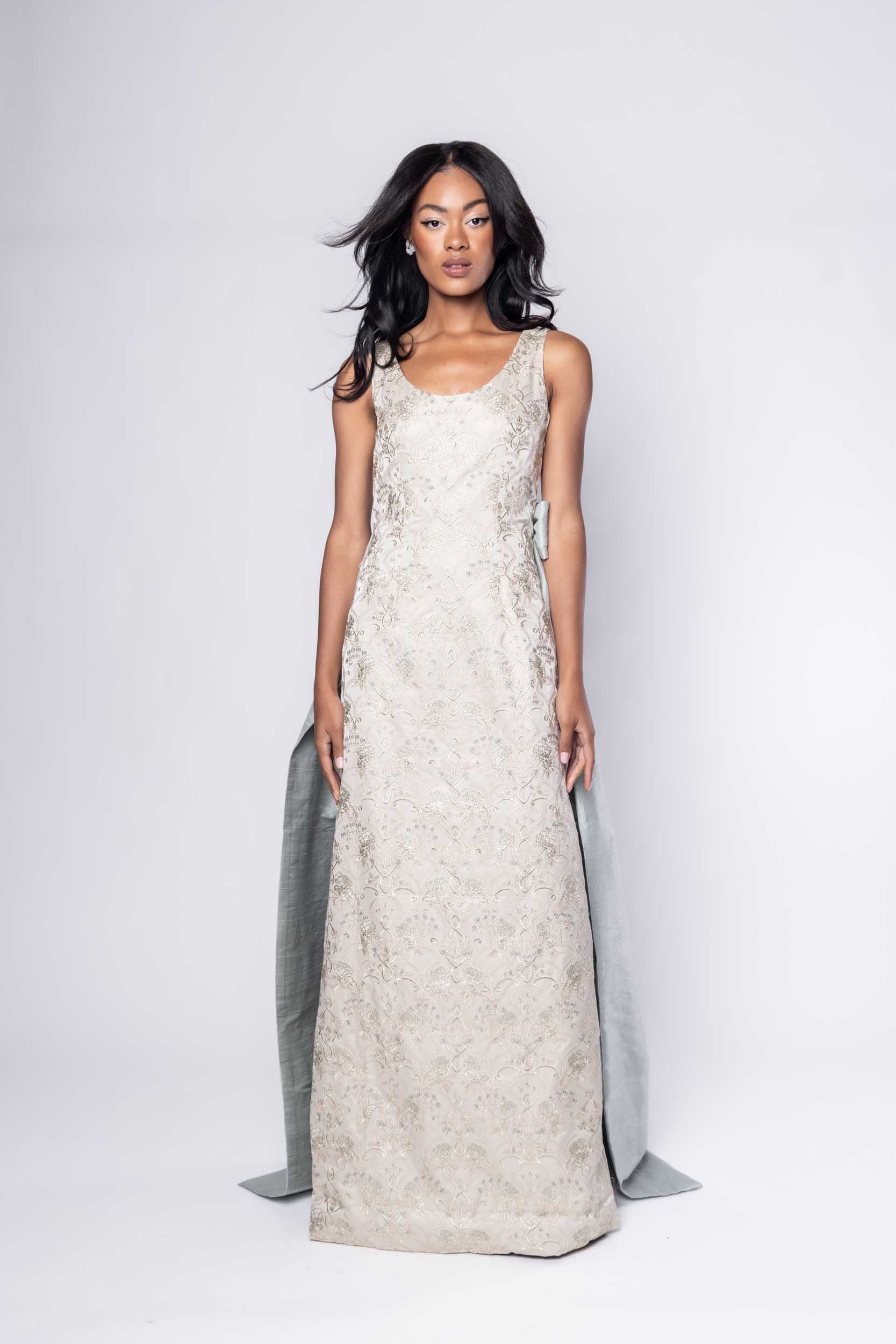 Beautiful model in an embroidered, ornate Sujata Gazder gown with large blue bow train - front view