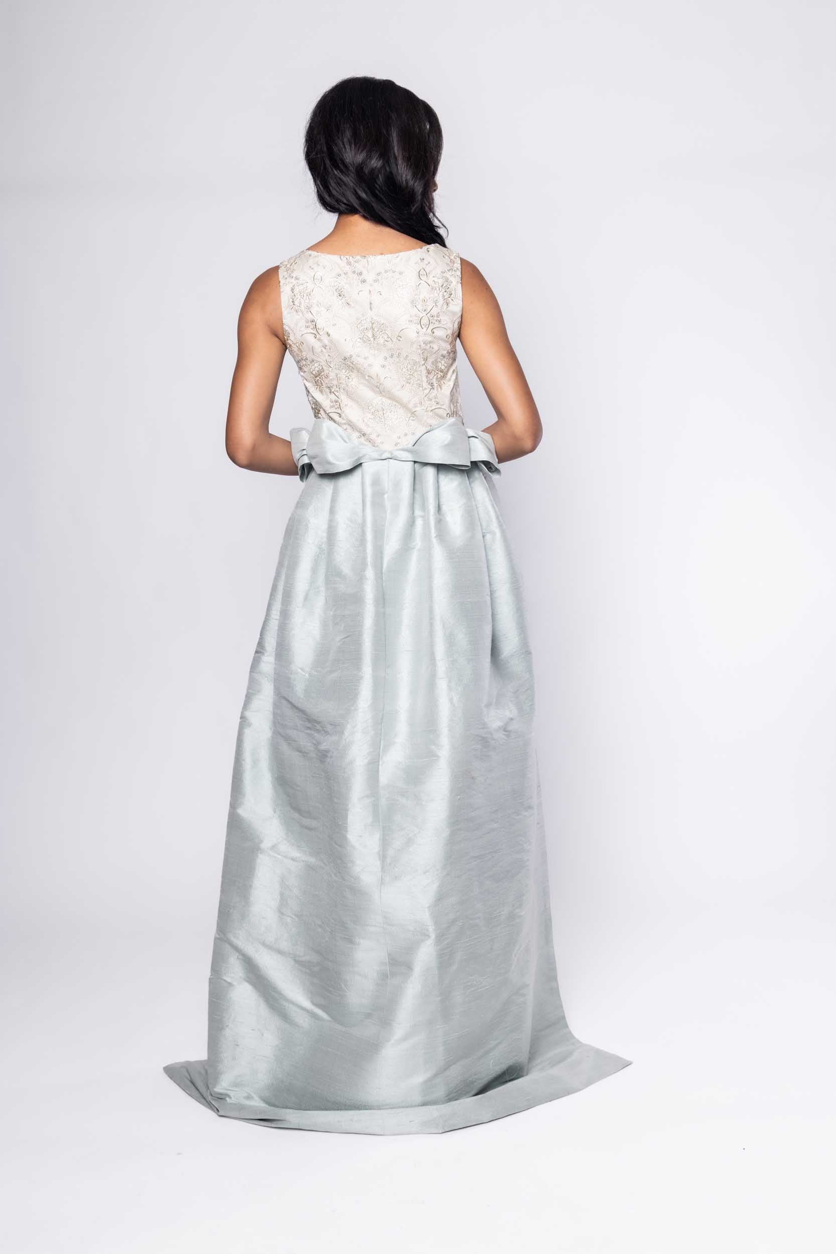 Beautiful model in an embroidered, ornate Sujata Gazder gown with large blue bow train - back view