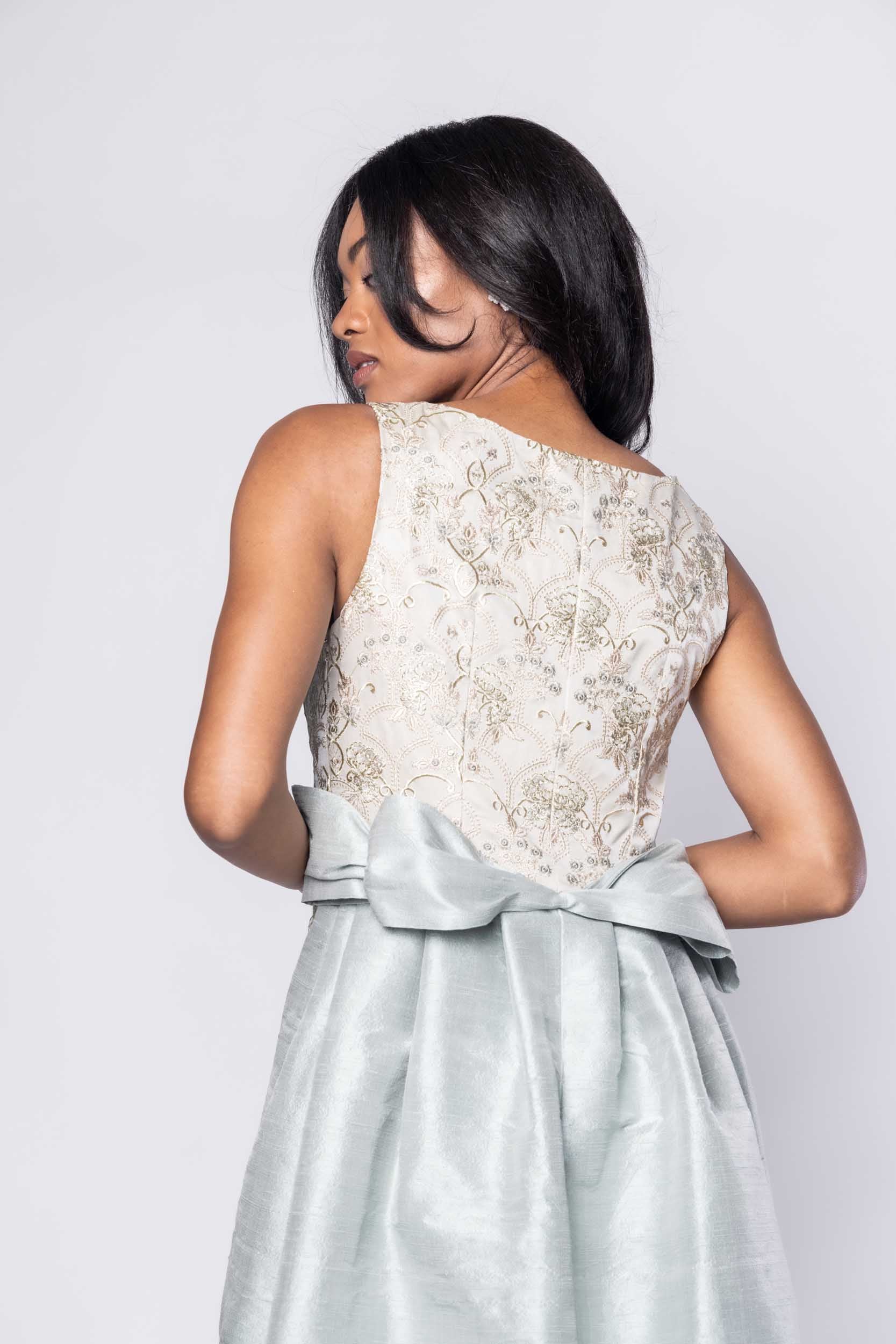 Beautiful model in an embroidered, ornate Sujata Gazder gown with large blue bow train - back view
