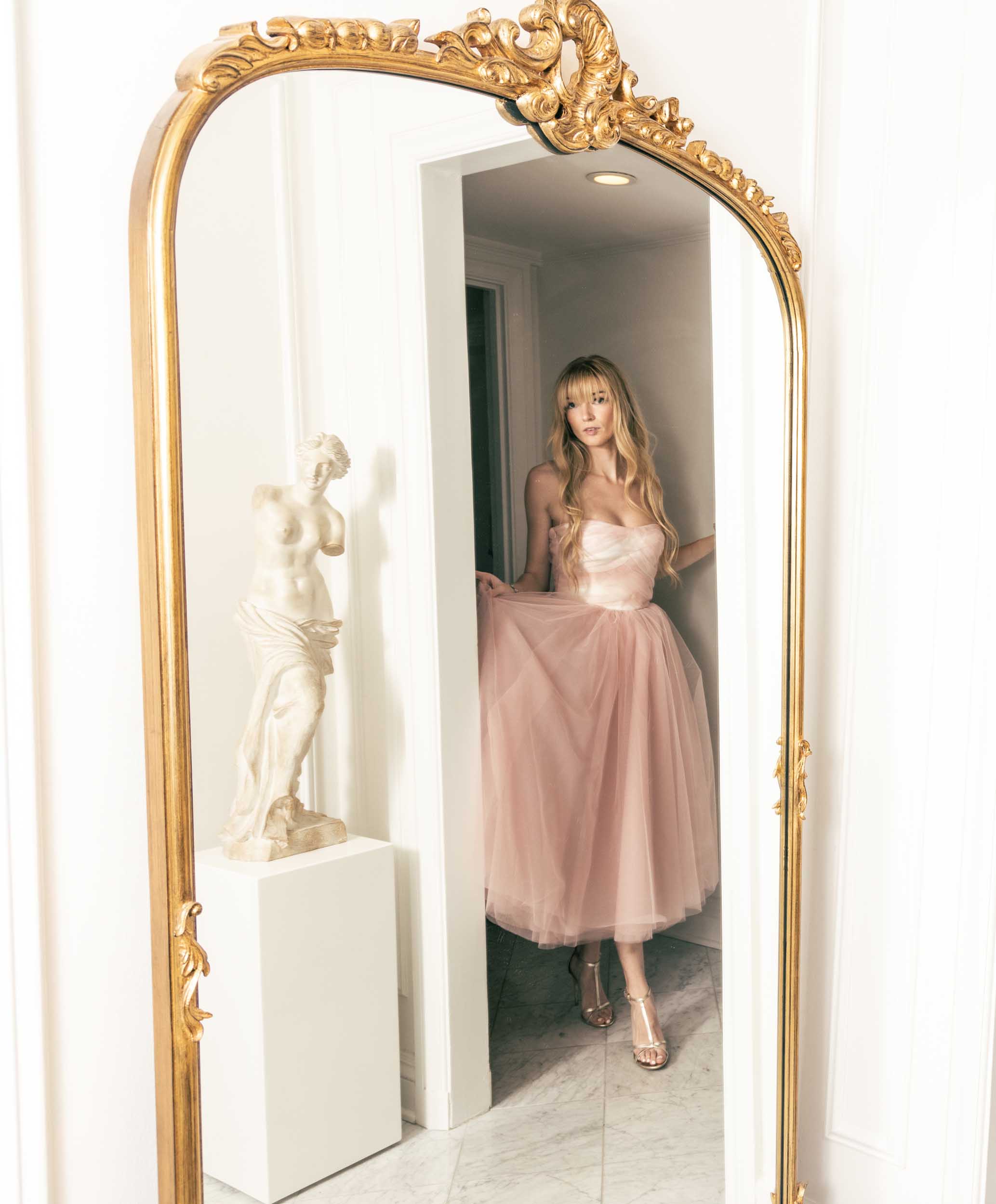 Beautiful model in a chic mirror with statue in a pink tulle Sujata Gazder tea-length dress