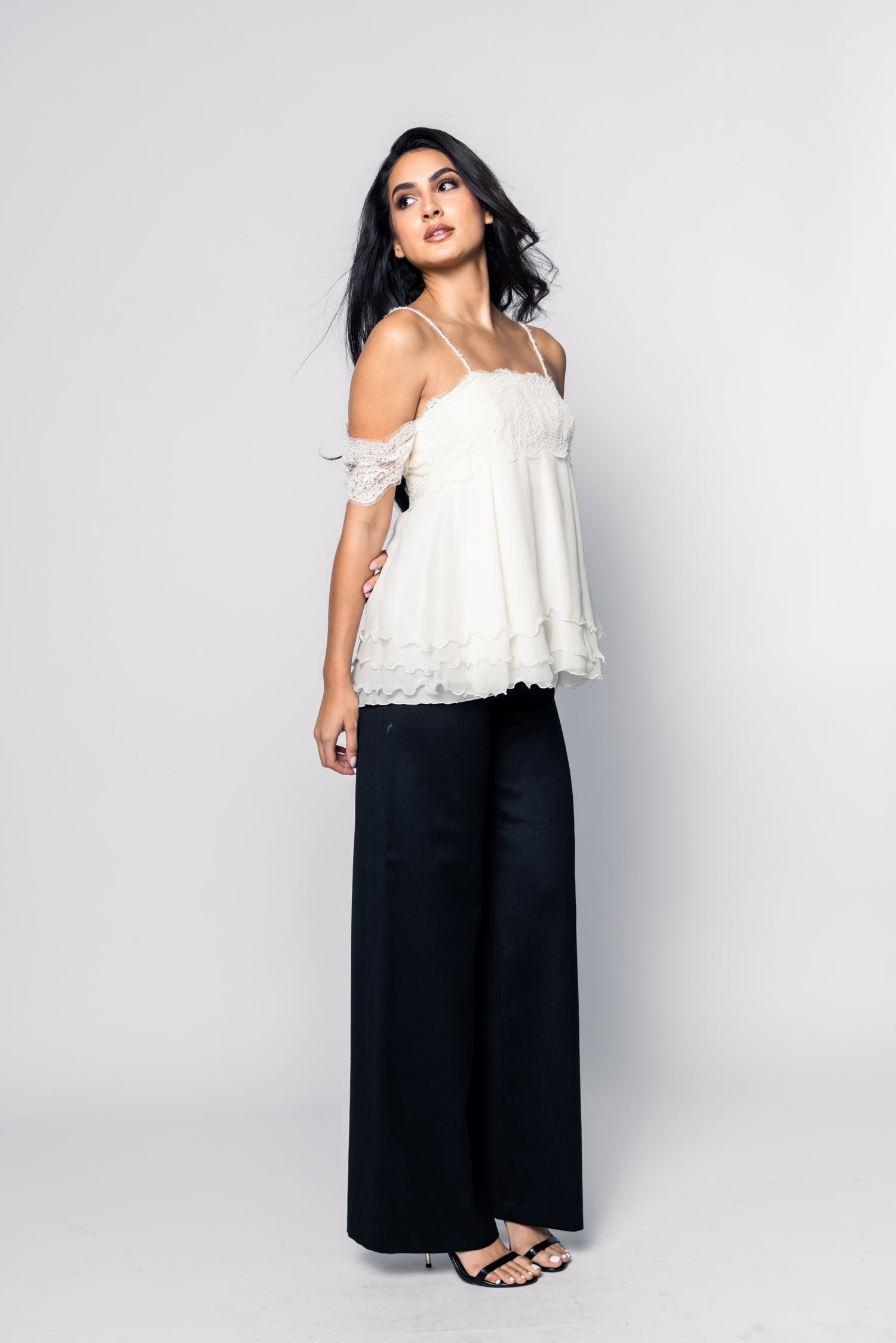 Woman wearing a white top and black pants on a white background