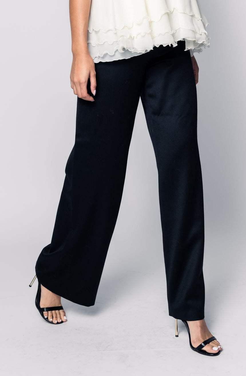 Woman wearing a white top and black pants on a plain background