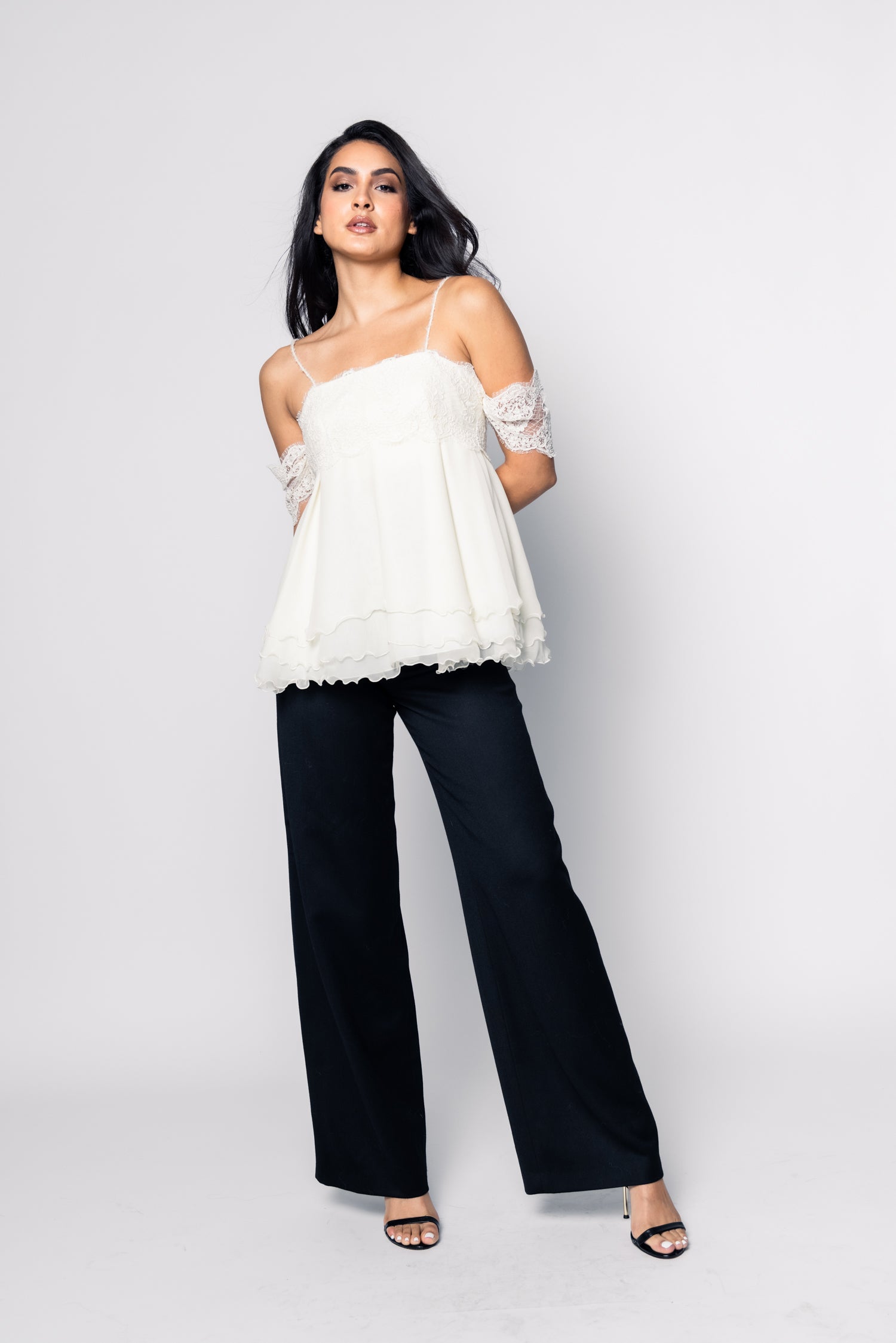 Woman wearing a white strapless top and black pants on a white background