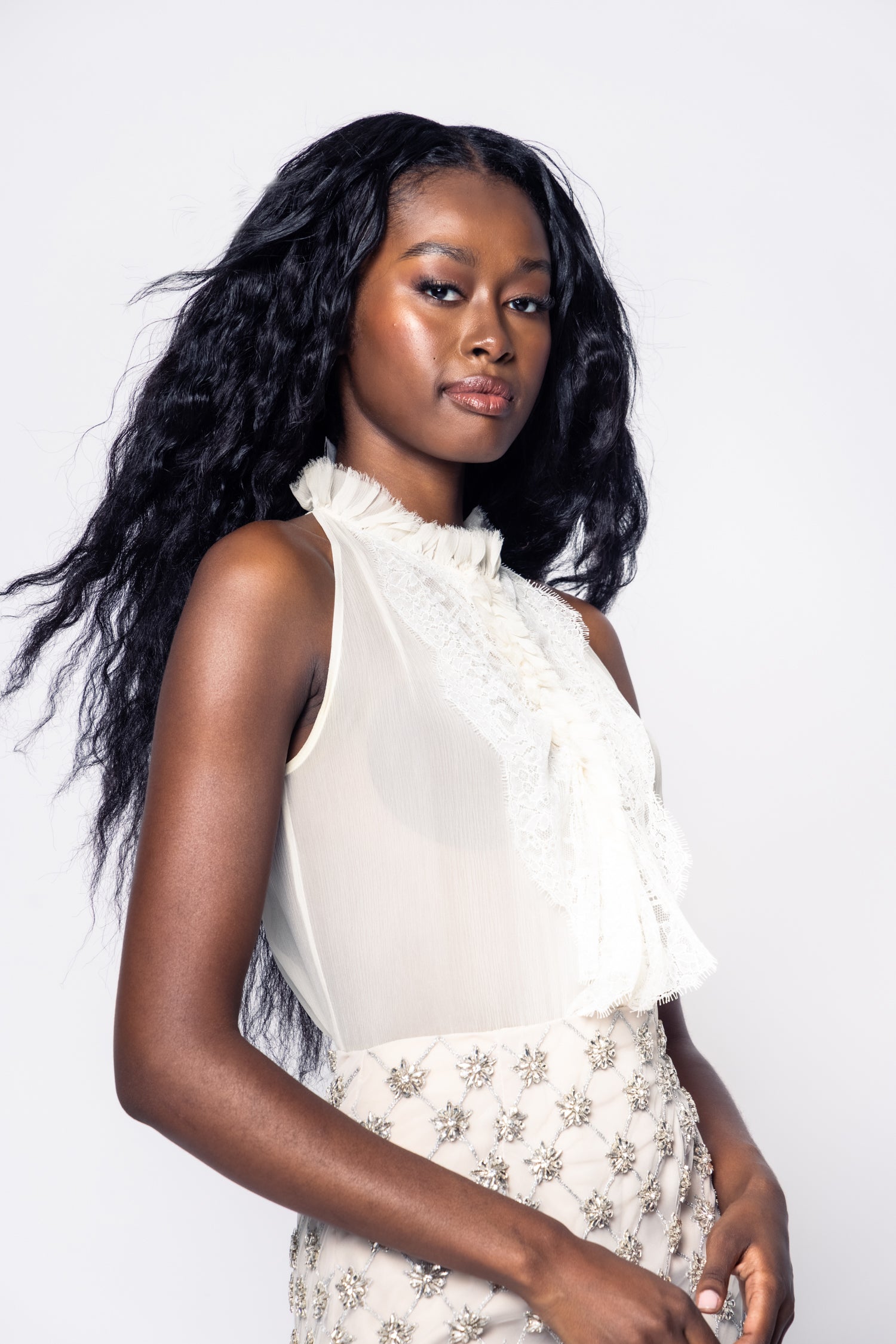 Woman wearing a white blouse and floral skirt against a white background