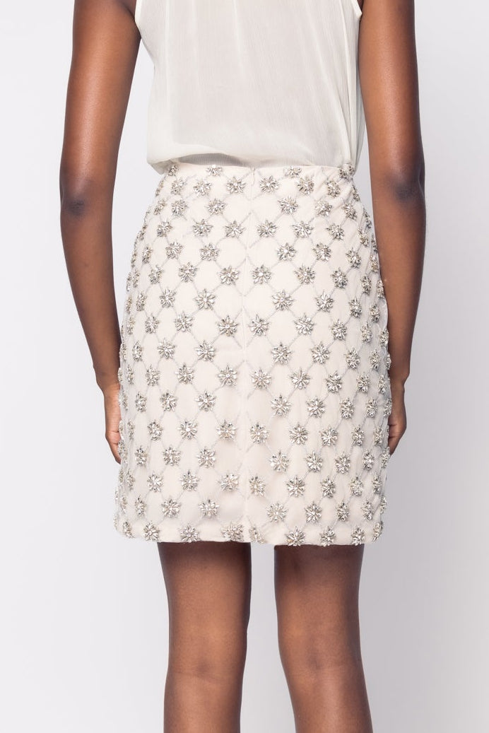Woman wearing a white halter top and patterned skirt on a plain background