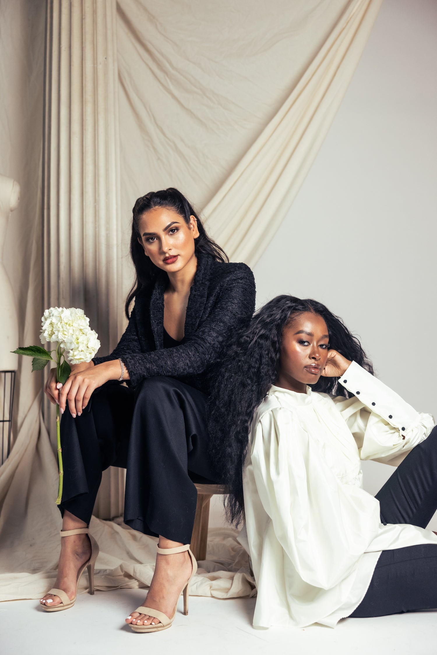 Two women in black and white separates in a studio setting