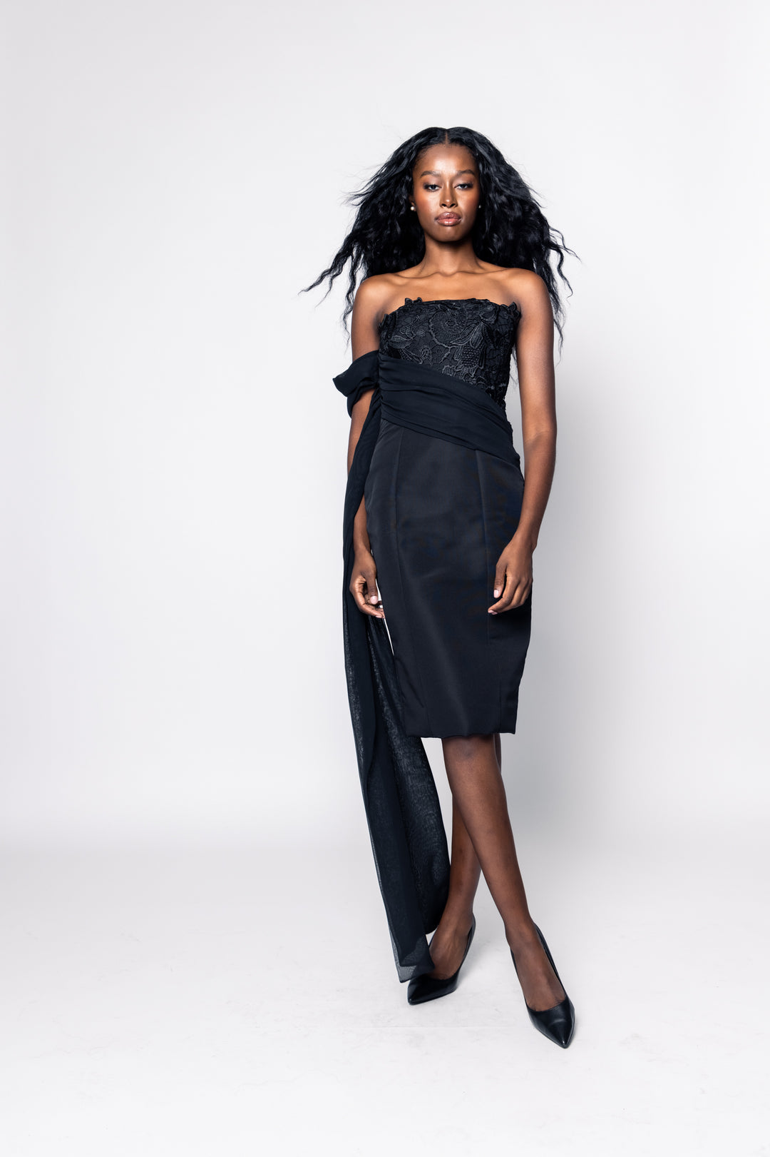 Woman wearing a black strapless dress with a flowing skirt on a white background