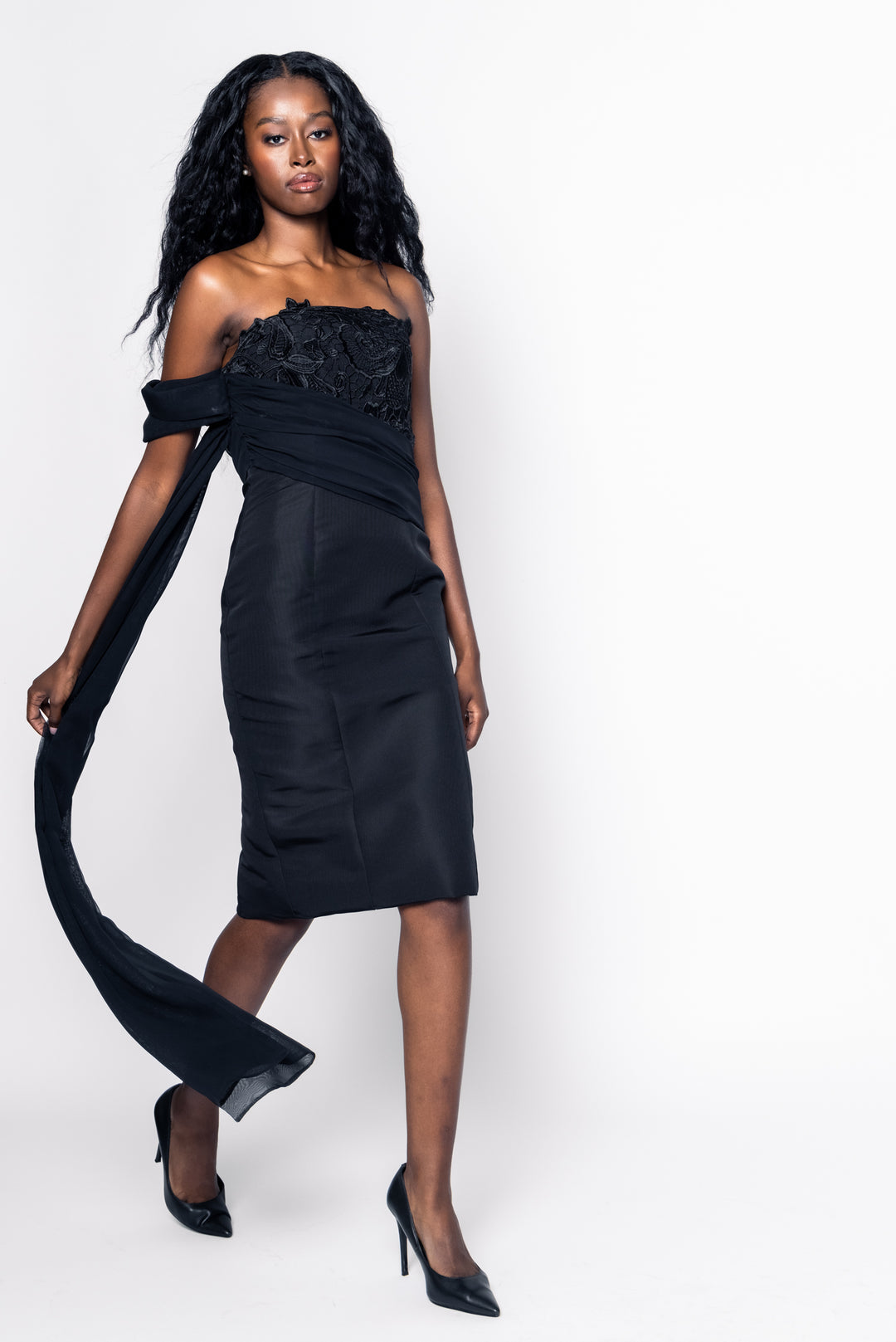 Woman wearing a black one-shoulder dress with a long train on a white background