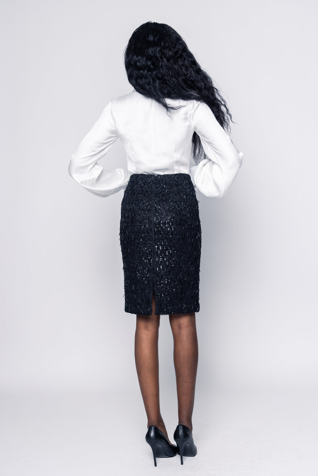 Person wearing a white blouse and black skirt on a plain background