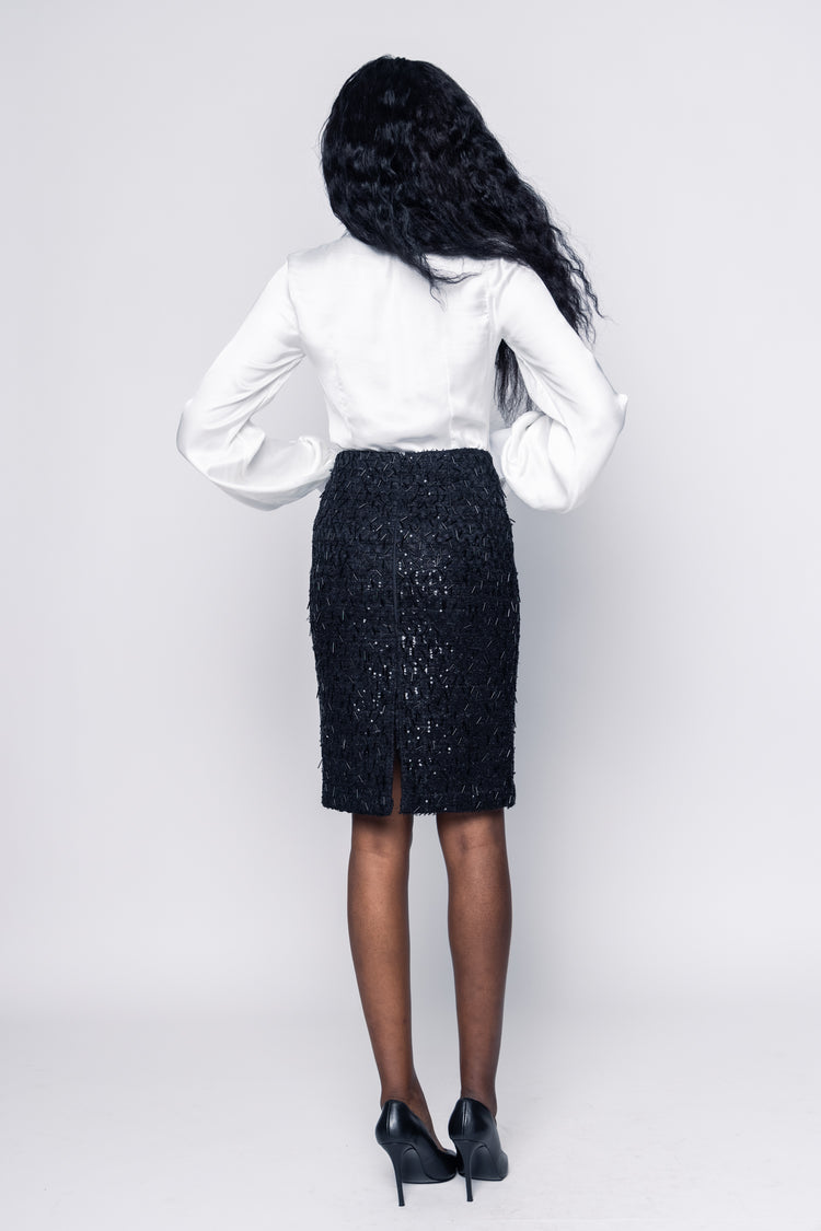 Person wearing a white blouse and black skirt on a plain background