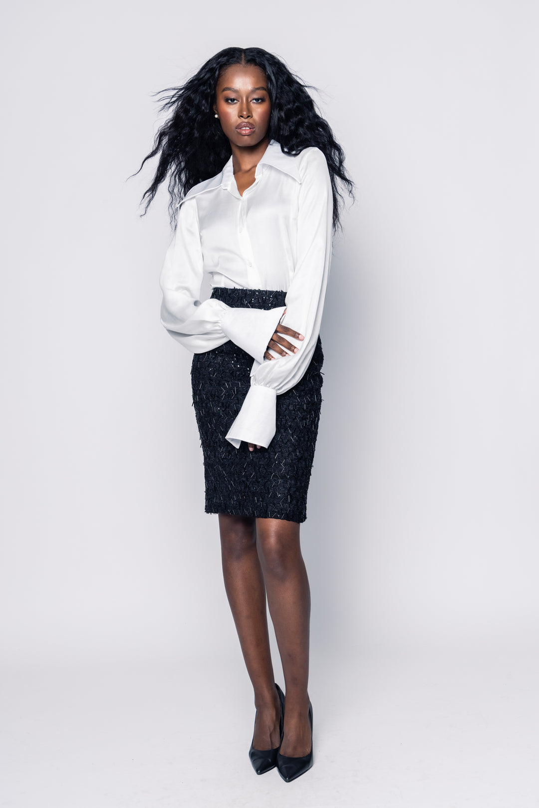 Woman wearing a white blouse and black patterned skirt on a white background