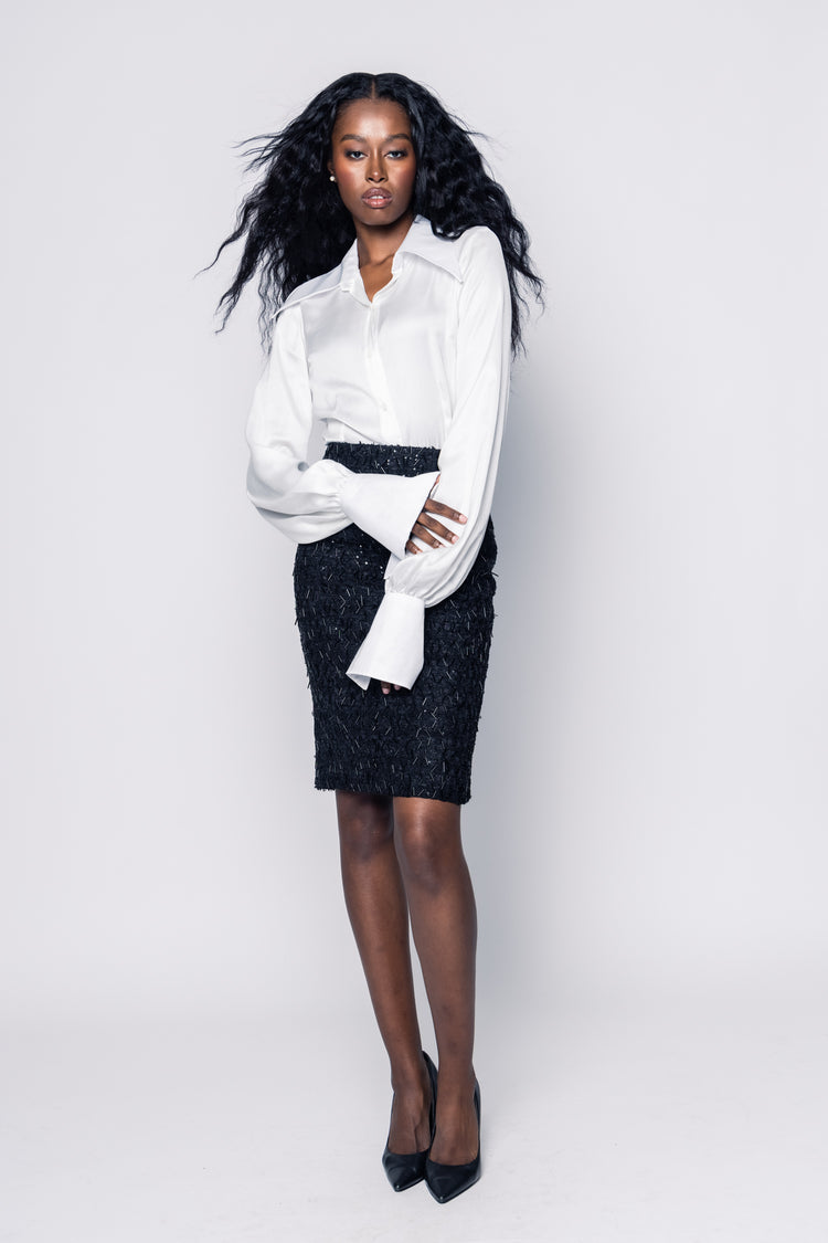 Woman wearing a white blouse and black patterned skirt on a white background