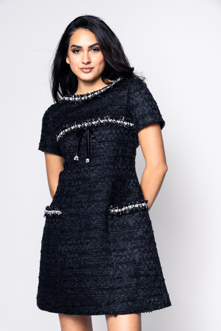 Woman wearing a black dress with silver embellishments on a white background