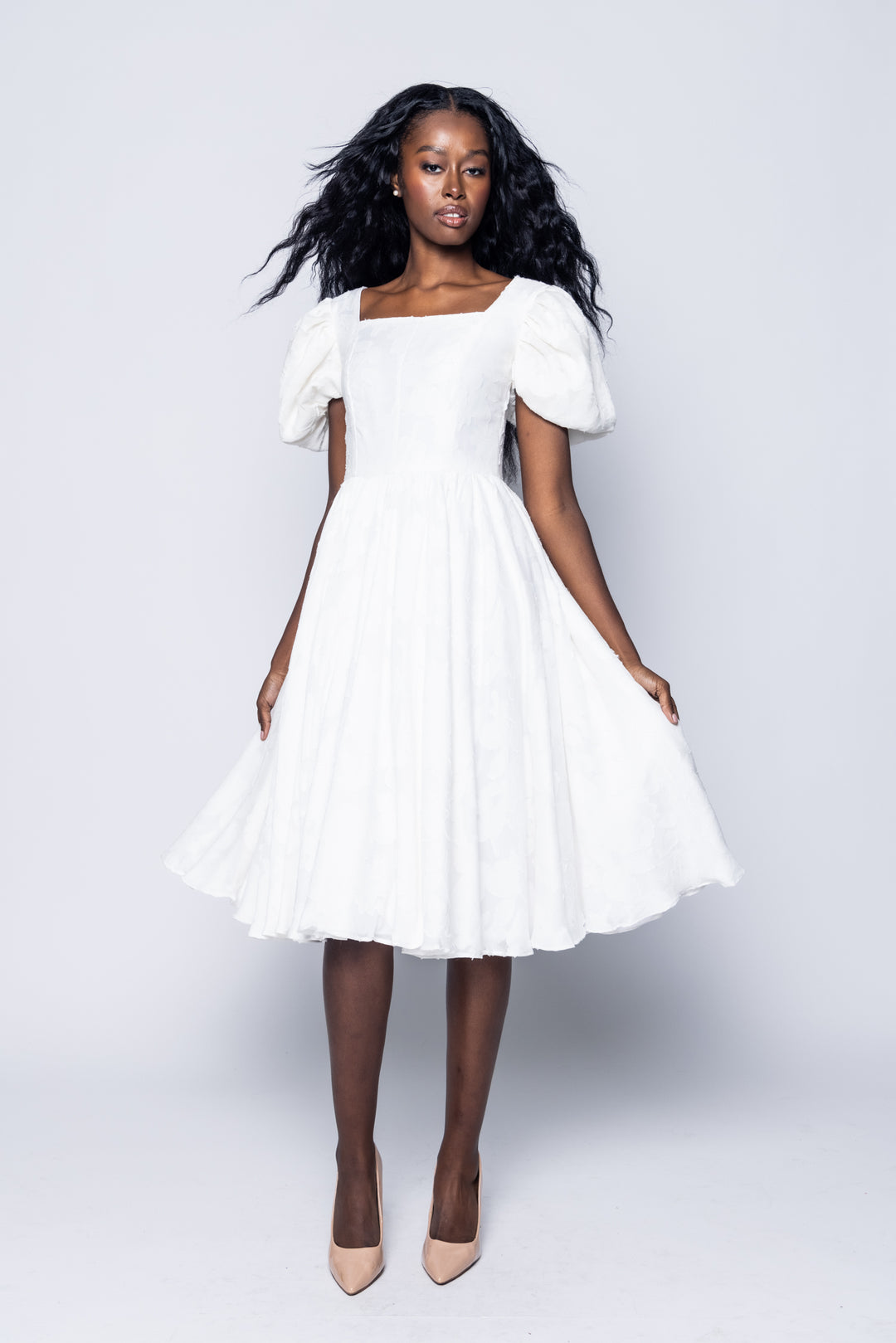 Woman wearing a white dress against a plain background