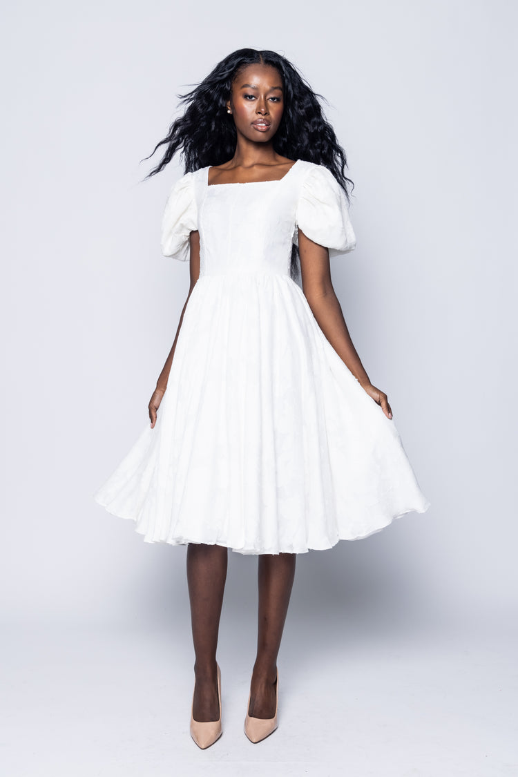 Woman wearing a white dress against a plain background