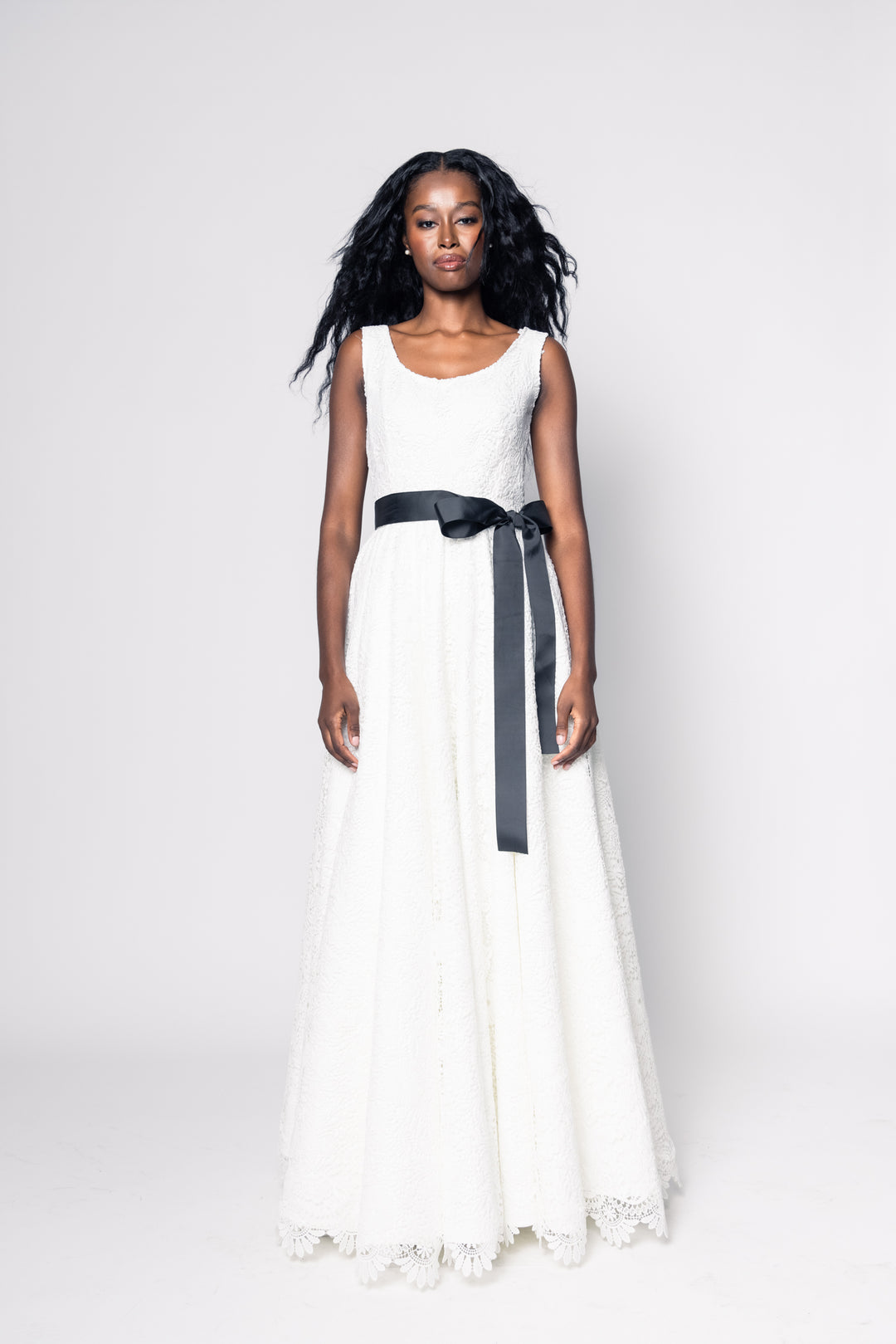 Woman wearing a white dress with a black belt on a white background