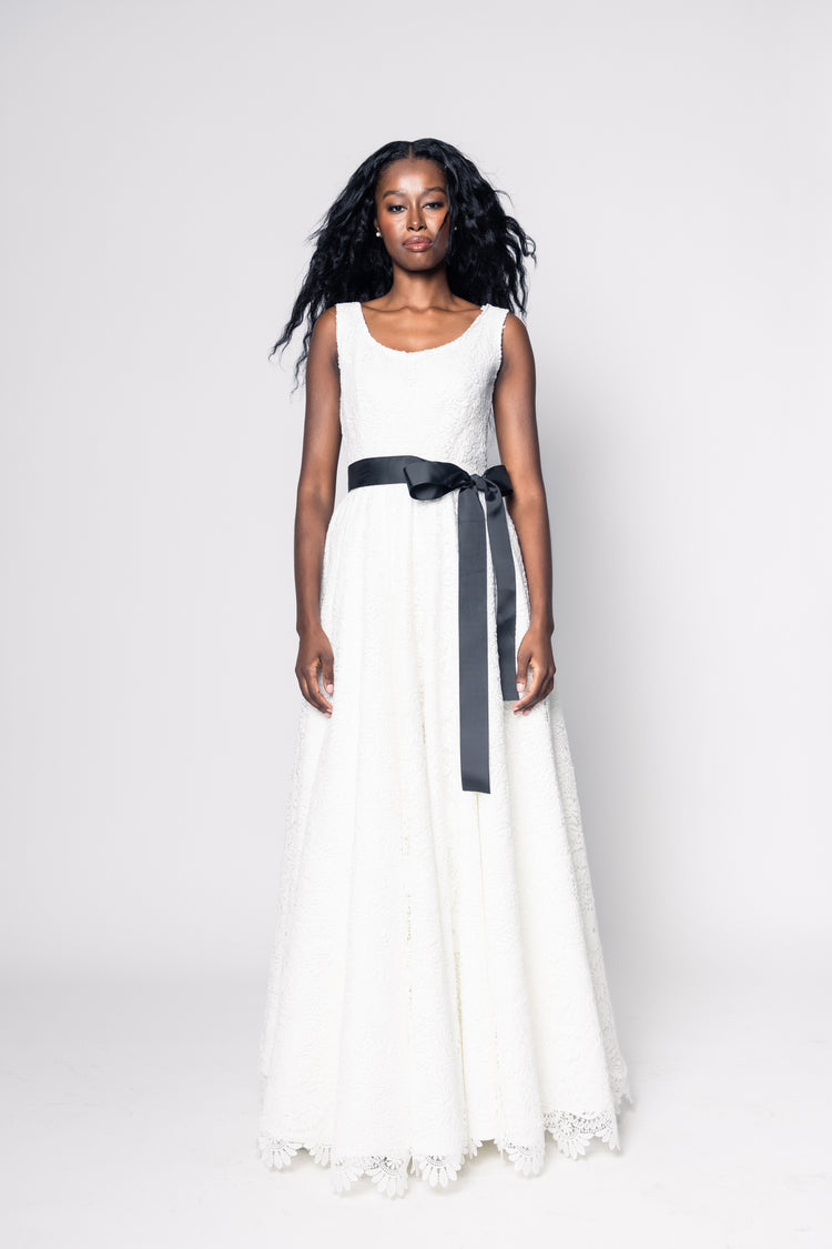 Woman wearing a white dress with a black belt on a white background