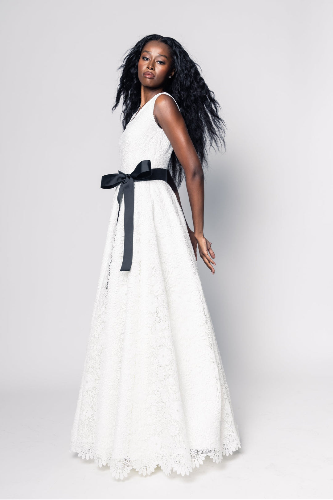 Woman wearing a white dress with a black belt on a plain background