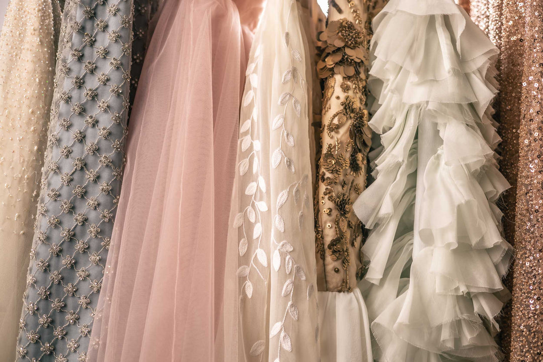 Rack of many beautiful pastel and ornate beaded and embroidered gowns on a rack