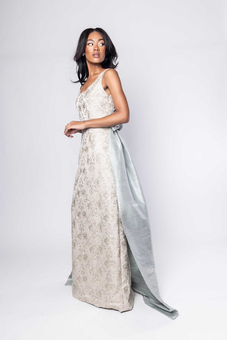Beautiful model in an embroidered, ornate Sujata Gazder gown with large blue bow train - side view